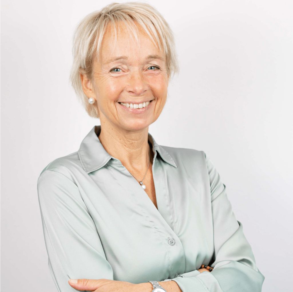 Hanna Roelofs: Porträtfoto einer lächelnden Frau mittleren Alters mit kurzem, blondem Haar. Sie trägt ein hellgrünes Hemd und hat die Arme locker vor der Brust verschränkt. Ihre Position ist Technische Systemplanung.